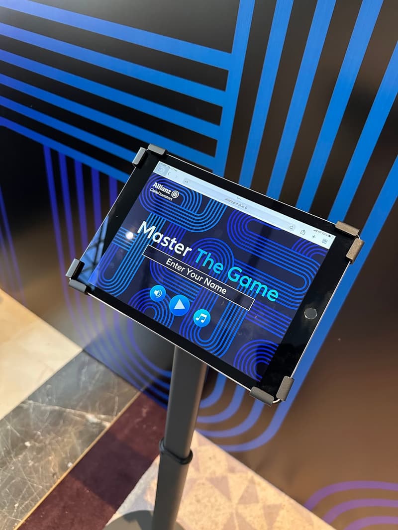 An iPad on a floor stand running an interactive event game against a branded booth backdrop