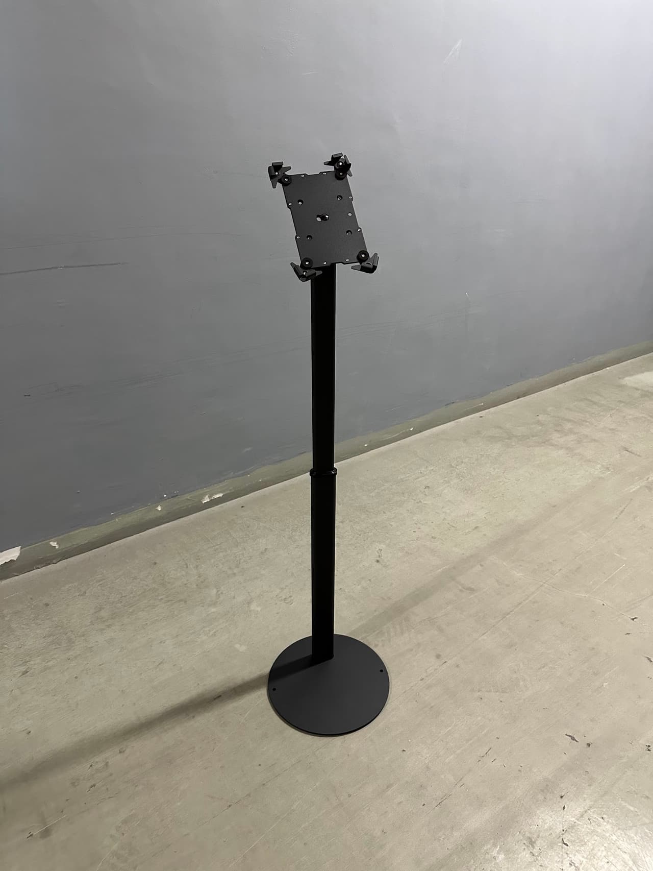 Black round-base iPad floor stand seen at an angle