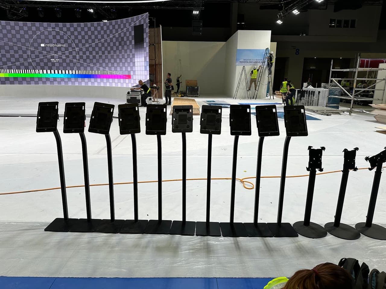 A long row of iPad floor stands set out on the exhibition floor during booth build-up at MITEC