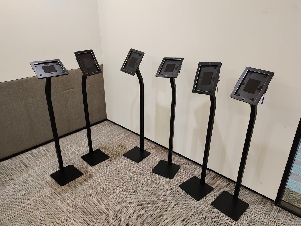 Six iPad floor stands lined up against a wall ready for dispatch