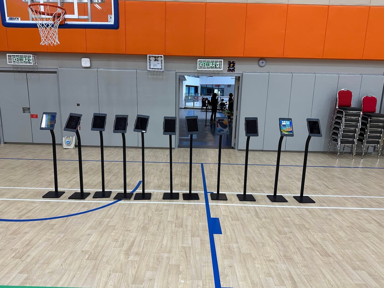 Ten iPad floor stands arranged across a school sports hall for an event