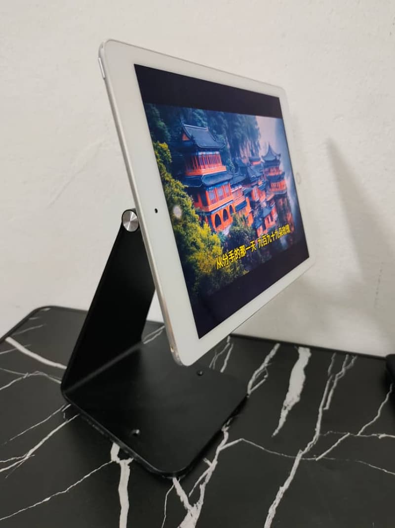 iPad held upright on a slim frameless table stand with nothing covering the screen