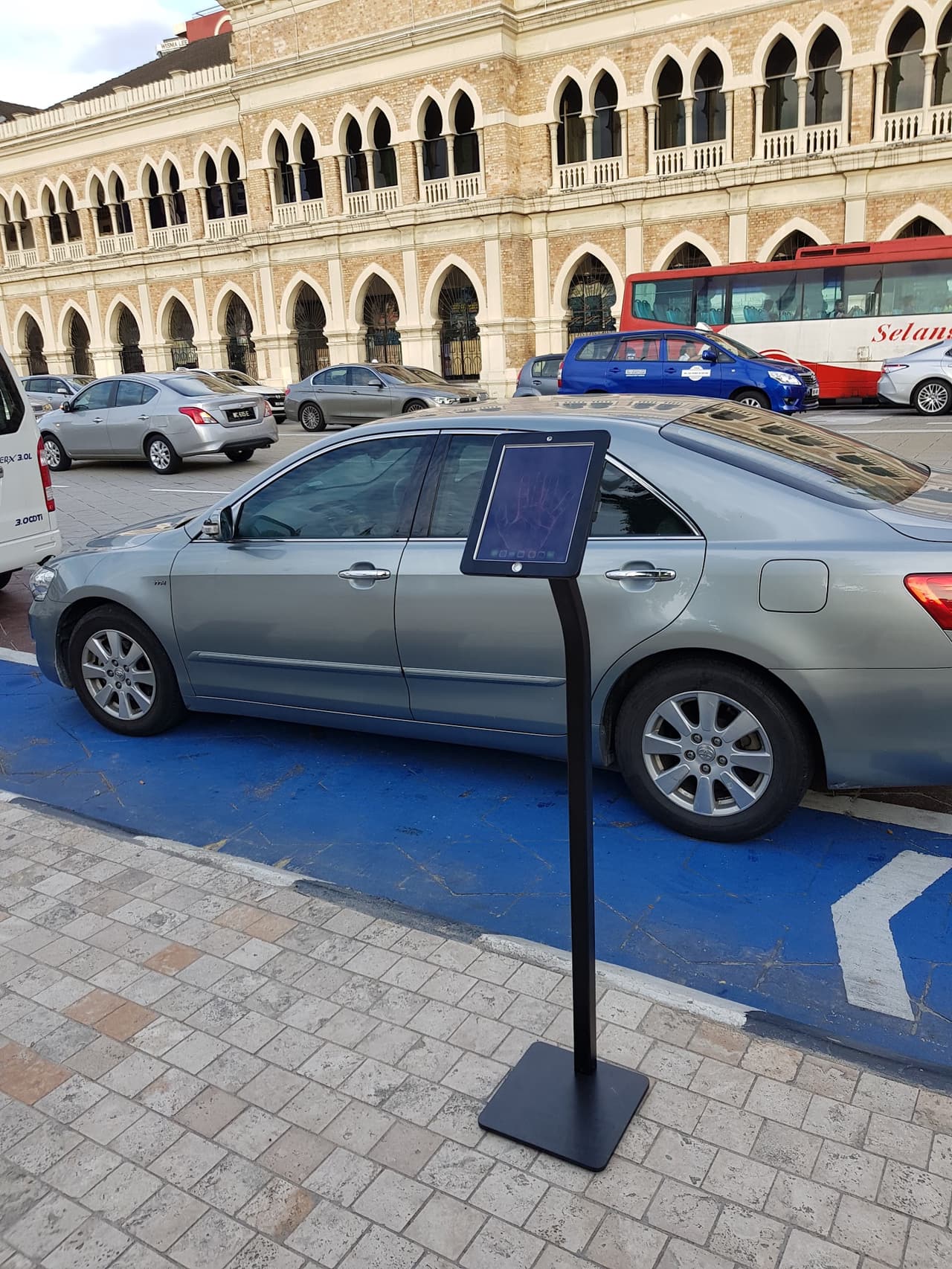iPad floor stand set up outdoors beside a car at a street-level roadshow