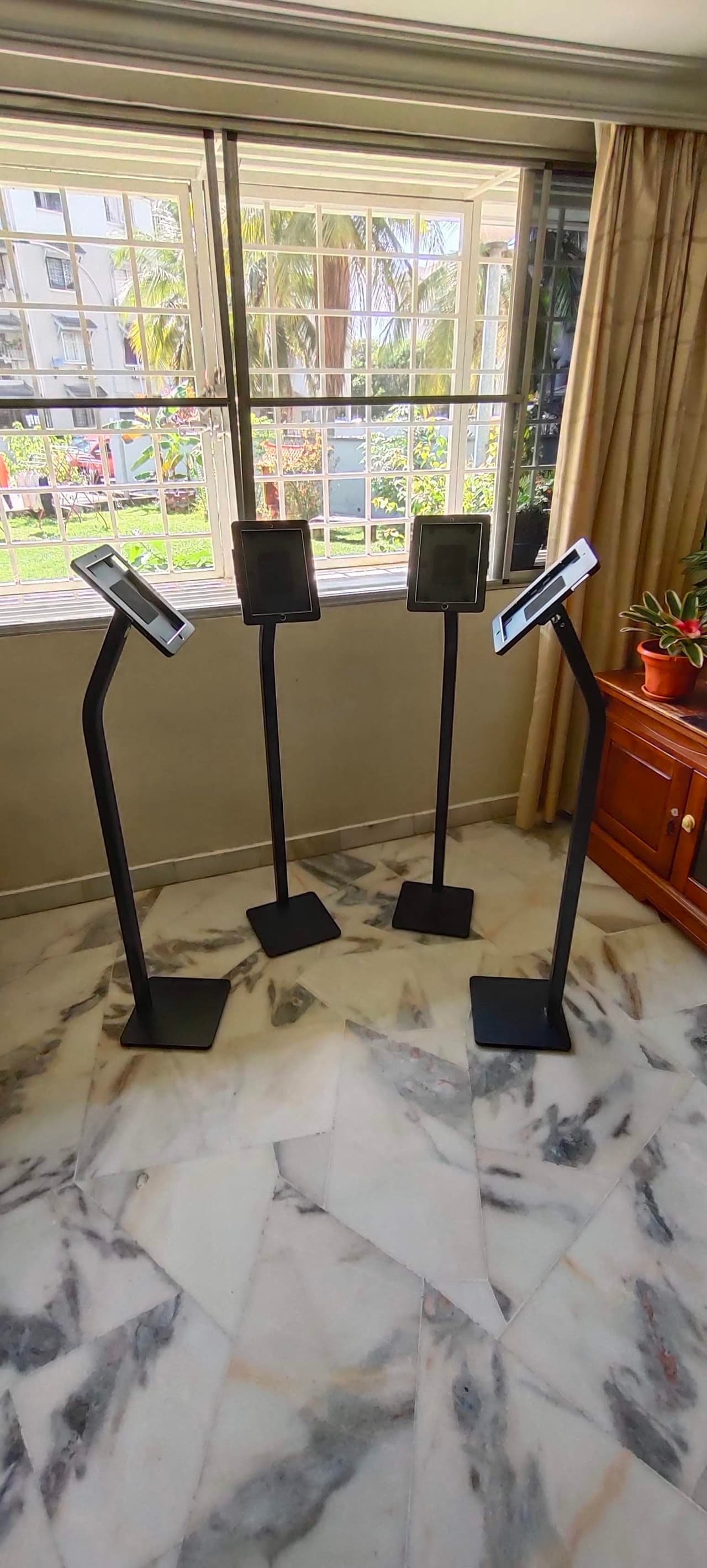 Four iPad floor stands arranged in a function room with marble flooring
