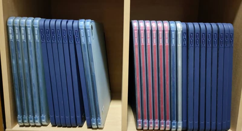 Two bays of shelving packed with iPads in blue and pink protective cases