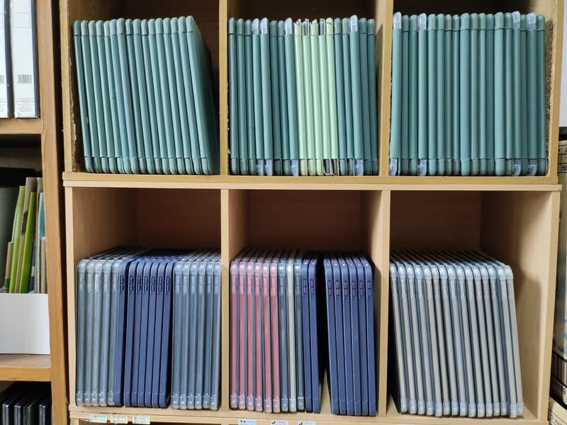 Shelving bays filled with iPads in green, blue and pink cases, sorted by row