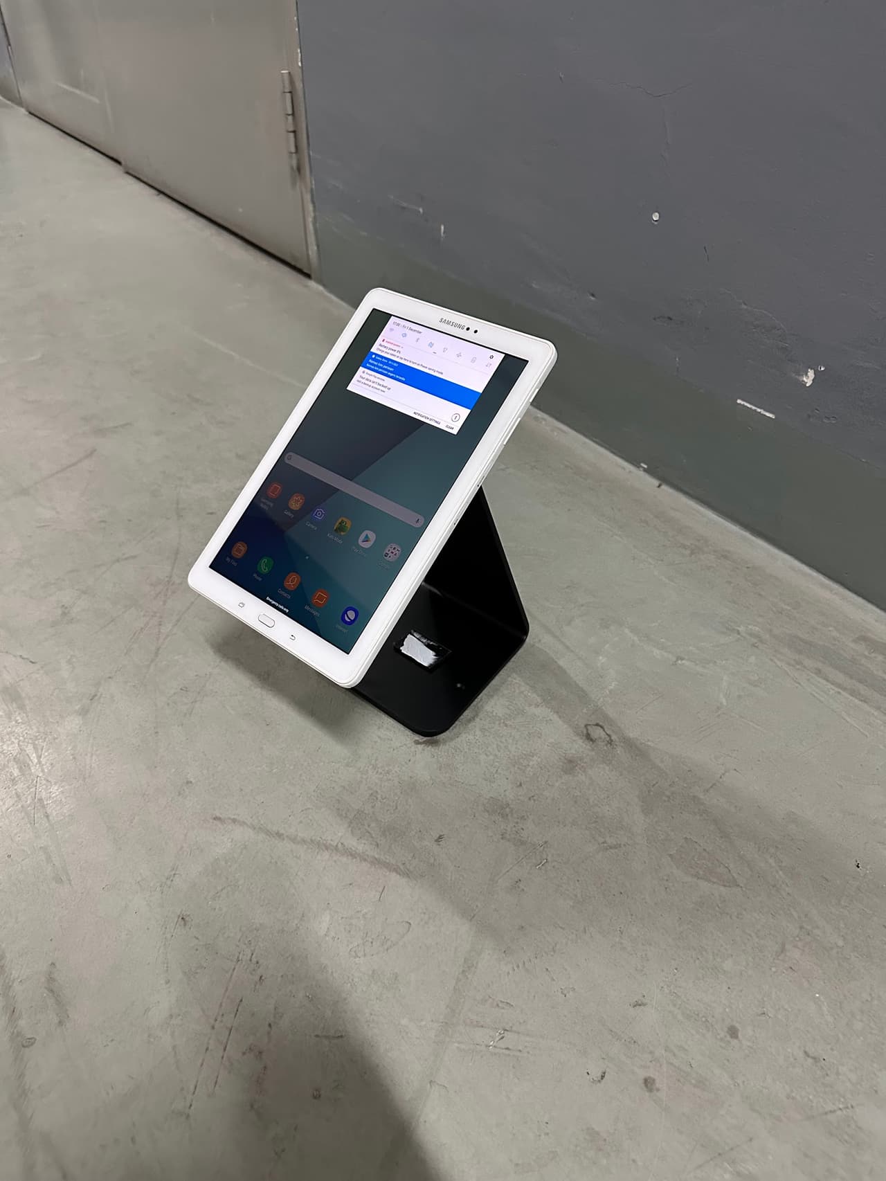 White tablet mounted on a black desk stand at an angle
