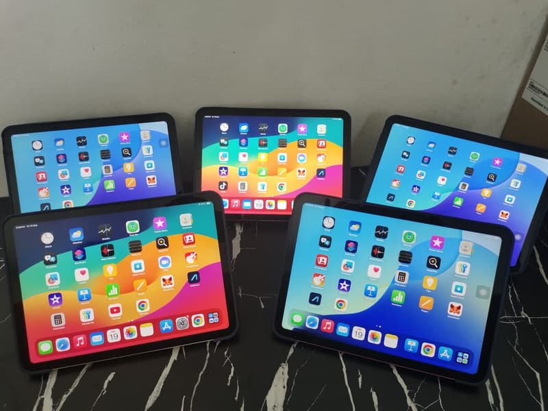 Five iPads standing side by side with their screens switched on